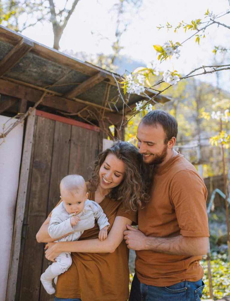 Smiling family with baby enjoying a sunny day outdoors, capturing a moment of affection and joy.